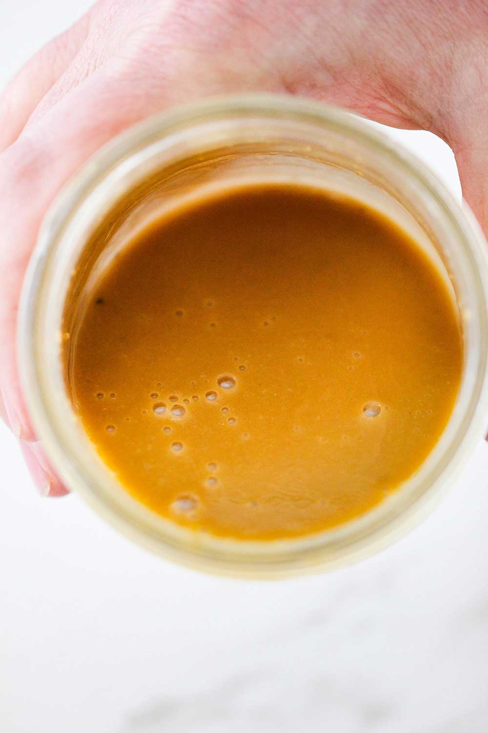 A hand holding a jar filled with homemade balsamic vinegar. 