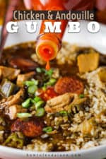 A bottle of cayenne hot sauce being poured into a white bowl of chicken and sausage gumbo.
