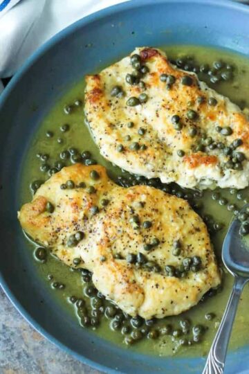 Classic Chicken Picatta in a blue dish next to a white and blue napkin