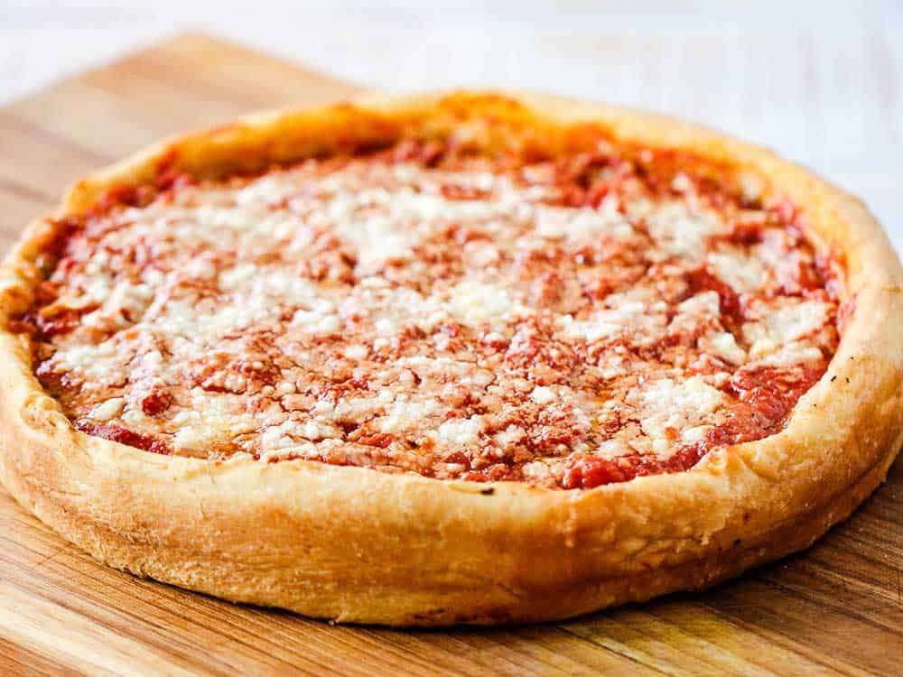 A fully cooked Chicago-style deep dish pizza on a cutting board. 