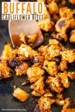 A baking dish filled with buffalo cauliflower bites with a wooden spoon inserted in the middle of them.