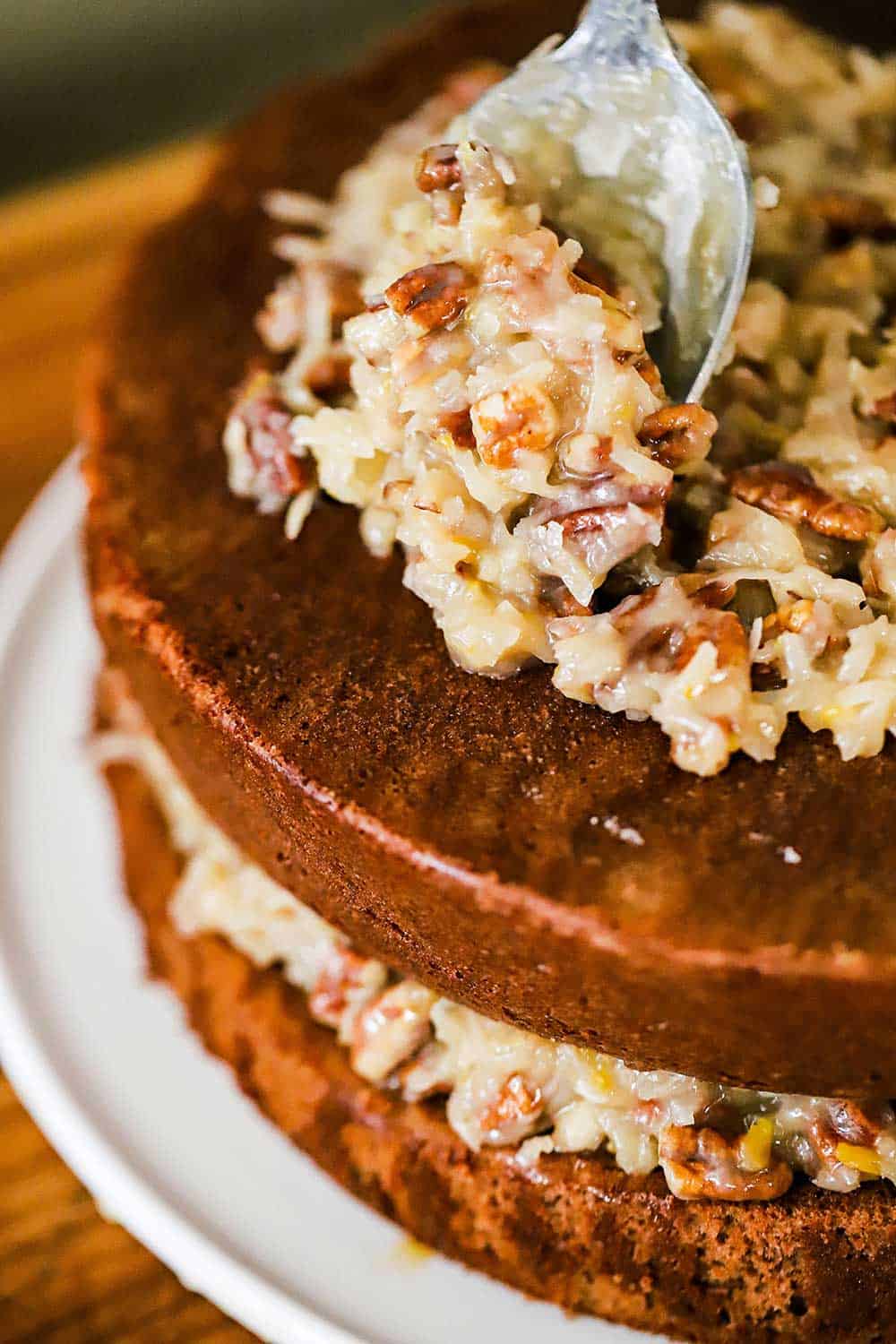 Coconut pecan frosting being spread on a 2-layered chocolate cake. 