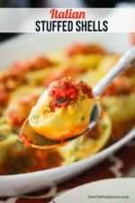 An Italian stuffed shell being held up on a large silver spoon.