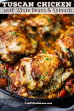 A close-up view of Tuscan chicken with white beans and spinach in a large black cast-iron skillet.