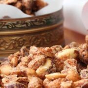 Naughty and Nice Spiced Nuts on a wood cutting board next to a tin with nuts
