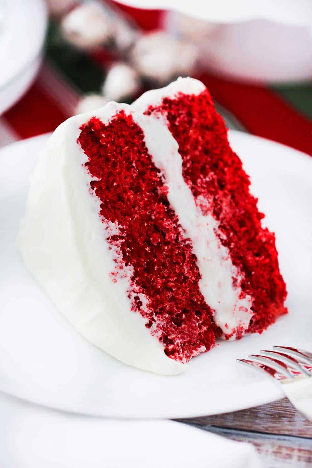 A large slice of red velvet cake on a white plate. 