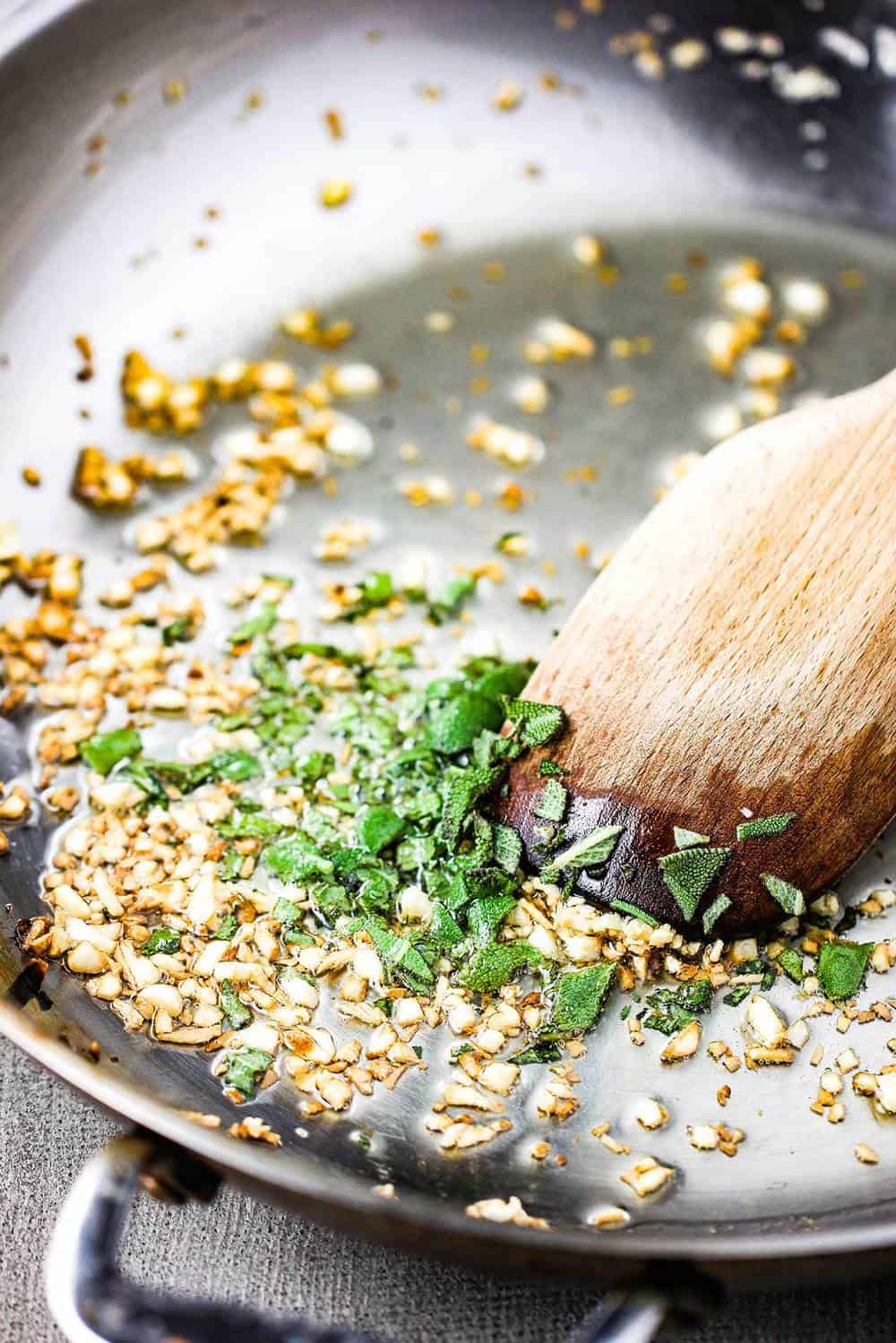 Garlic and sage sautéing in a skillet for sautéed white beans with garlic and sage