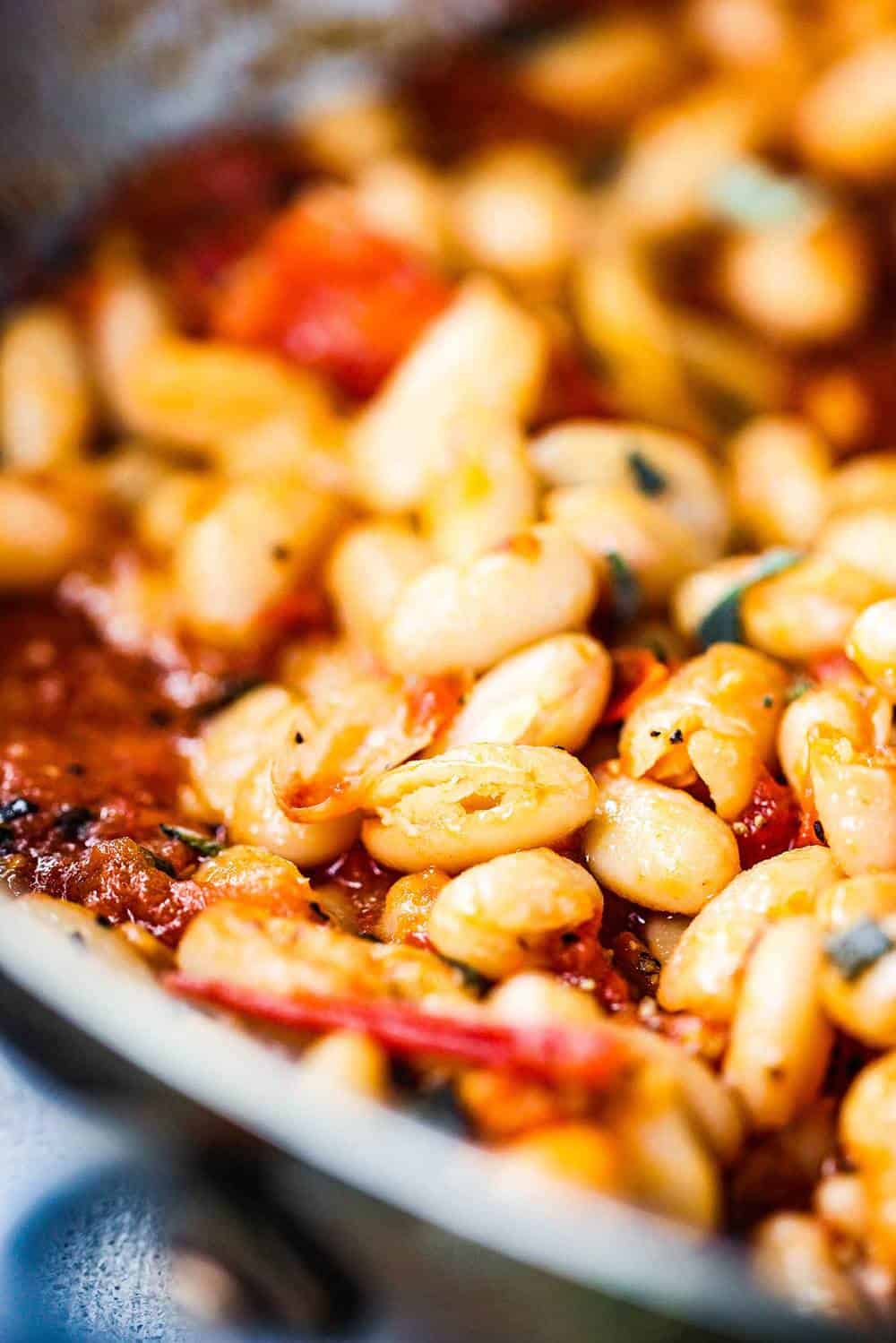 Sautéed white beans with garlic, sage and tomatoes in a skillet