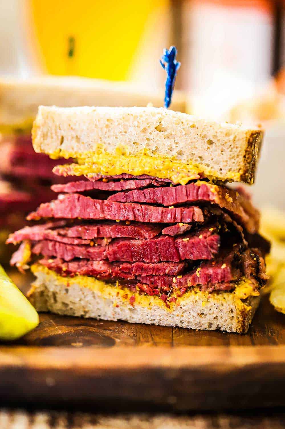 One half of a Wagyu pastrami sandwich sitting on a cutting board with the layers of meat exposed. 