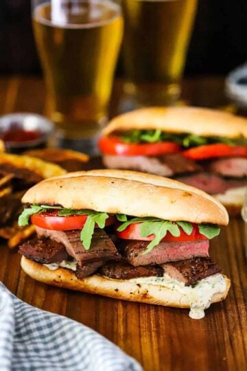 A Marinated Grilled Steak Sandwich on a wood cutting board