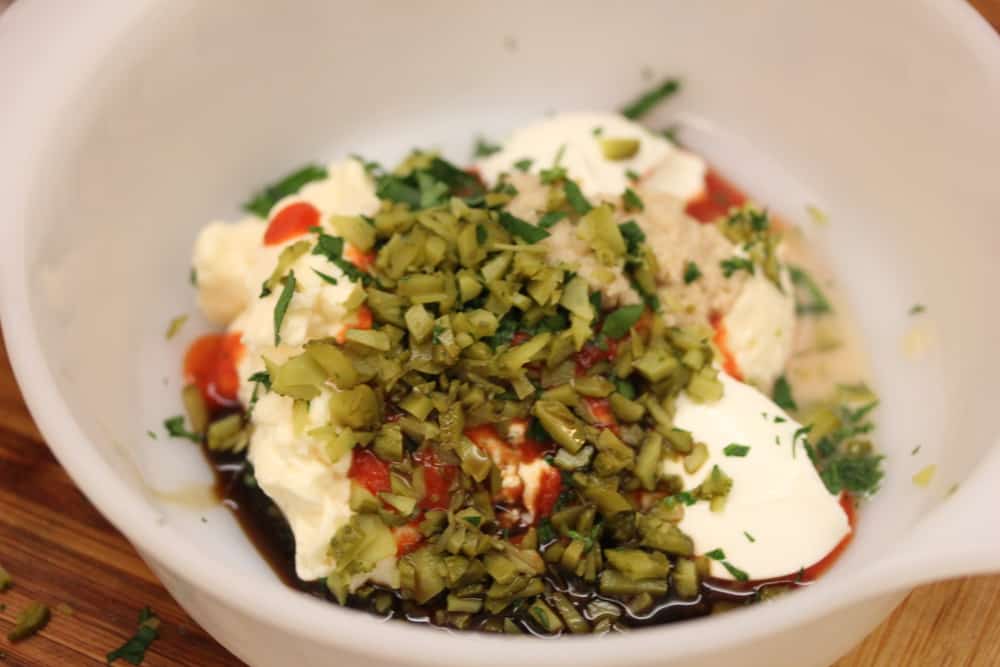 A bowl filled with mayonnaise, chopped pickles, and the other ingredients for homemade Russian dressing. 