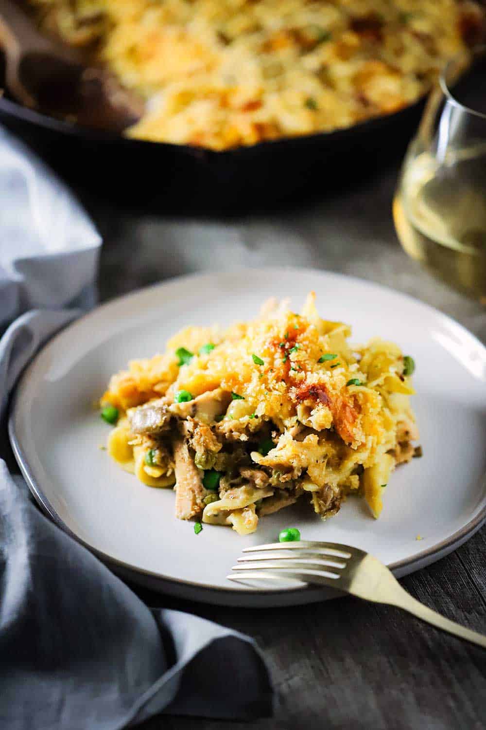 An individual plate with a helping of tuna casserole on it with a fork placed on the edge of the dish. 