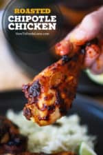 A hand, with a little sauce on the fingers, holding a roasted chipotle chicken leg up over a plate of cilantro-lime rice.