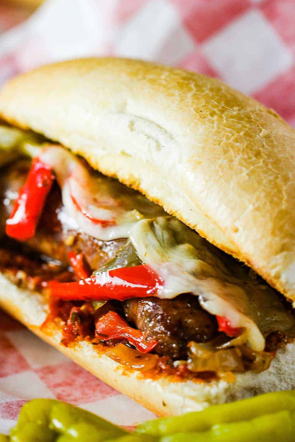 Sausage and Peppers hero on a checkered napkin. 