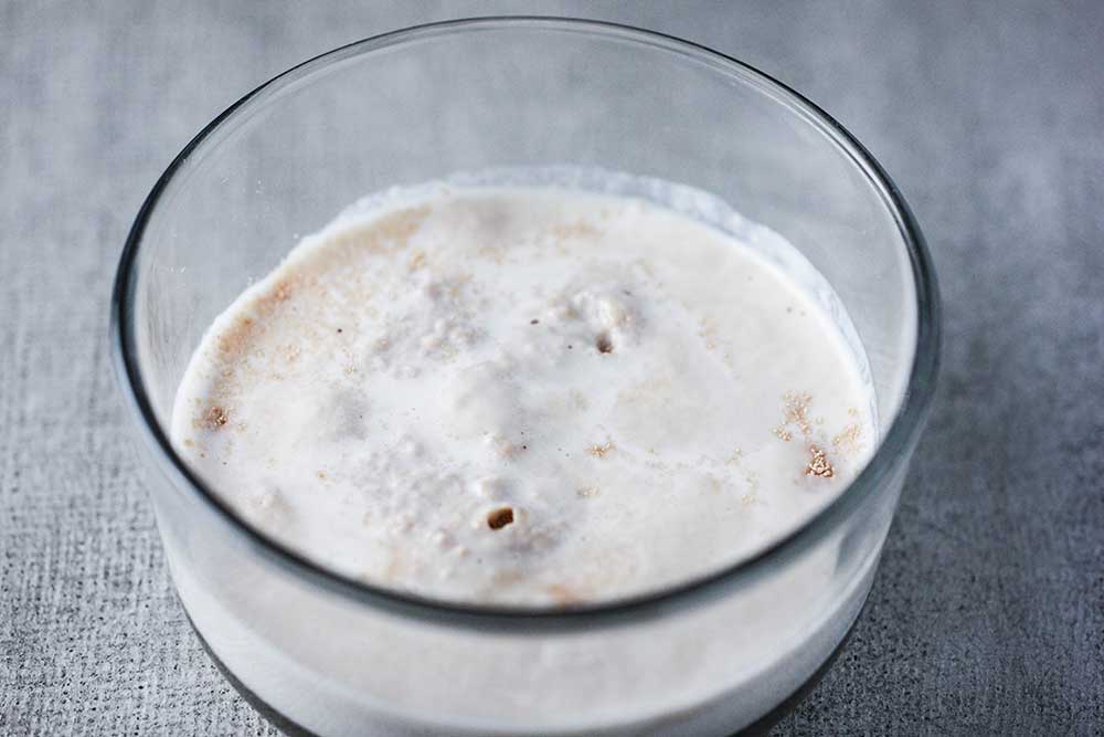 A small glass bowl of yeast bubbling in warm milk. 
