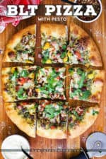 A overhead view of a BLT pizza cut into squares on a wooden cutting board with a small bowl of red pepper flakes and a bowl of Parmesan cheese nearby.
