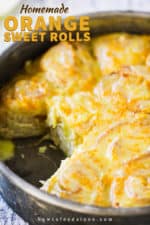 A metal pan holding homemade orange sweet rolls with two rolls missing.