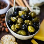 A small white oval bowl filled with green and black marinated olives.