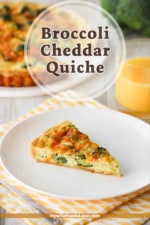 A slice of broccoli cheddar quiche on a white plate next to a glass of orange juice.