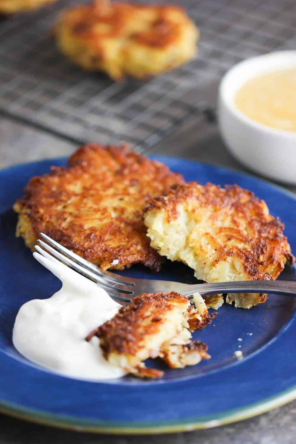 Classic latkes on a blue plate with a dollop of sour cream next to it