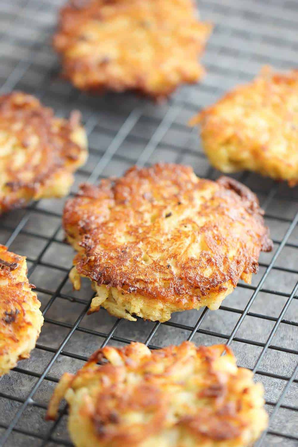 A close-up view of lightly fried classic latkes sitting on a wire baking rack