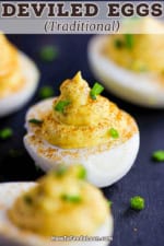 A traditional deviled egg garnished with paprika and snipped chives.