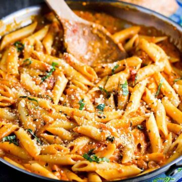 Penne alla vodka in a large skillet with a wooden spoon.