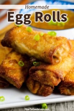 A plate filled with homemade egg rolls with chopped scallions sprinkled on top.