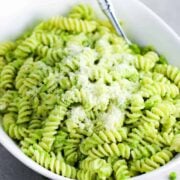 Fresh pea pesto pasta in a white serving bowl with a spoon