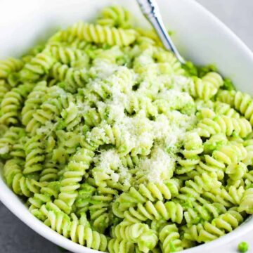 Fresh pea pesto pasta in a white serving bowl with a spoon