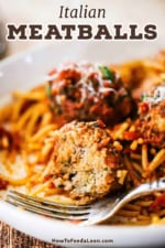 A close-up view of a heat-eaten Italian meatball sitting on spaghetti in a pasta bowl.