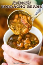A person using a ladle to transfer a helping of borracho beans into a small white cup filled with the beans.