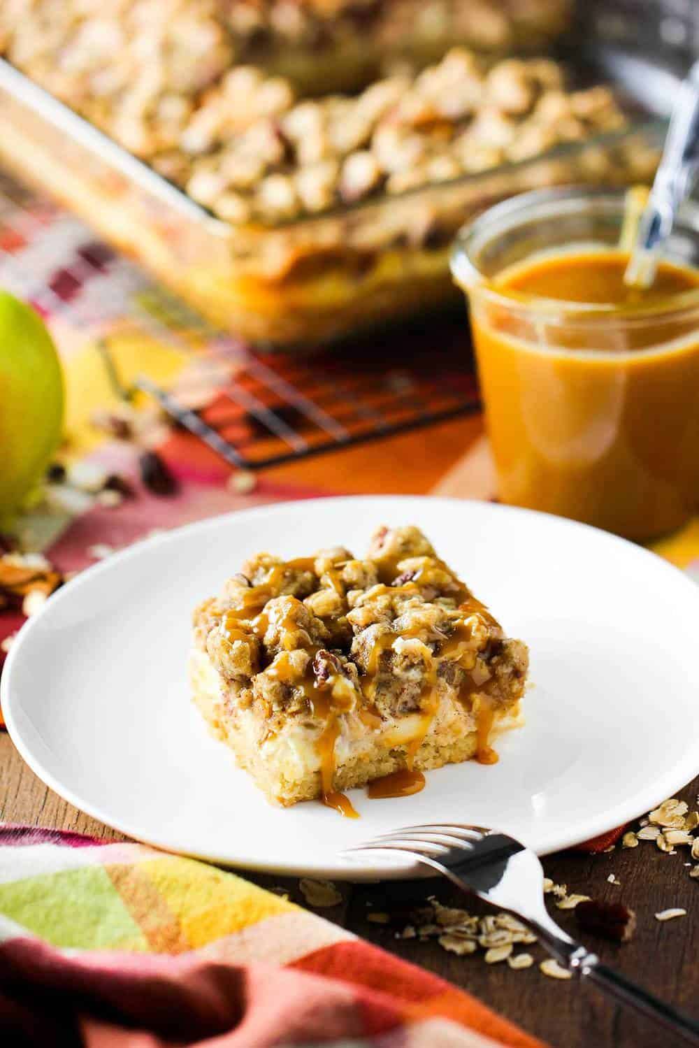 Cream cheese apple bars with pecan streusel on a white plate.