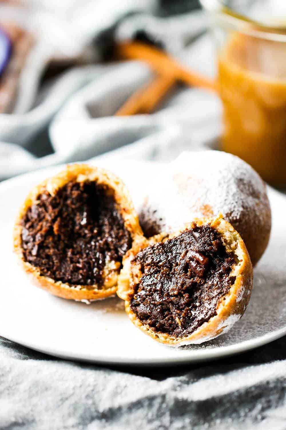 Deep fried brownie fritters that are open on a white plate.