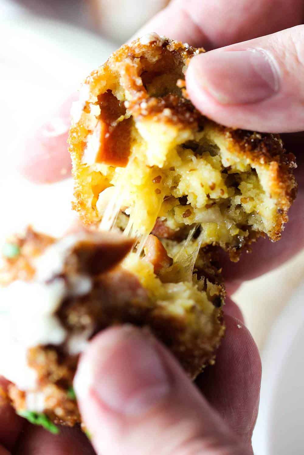 Smoked Sausage with Cheddar beignets being pulled apart with two fingers.