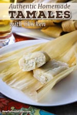 A close-up view of a homemade tamale that has been cut in half so the chicken and chilis filling is revealed.