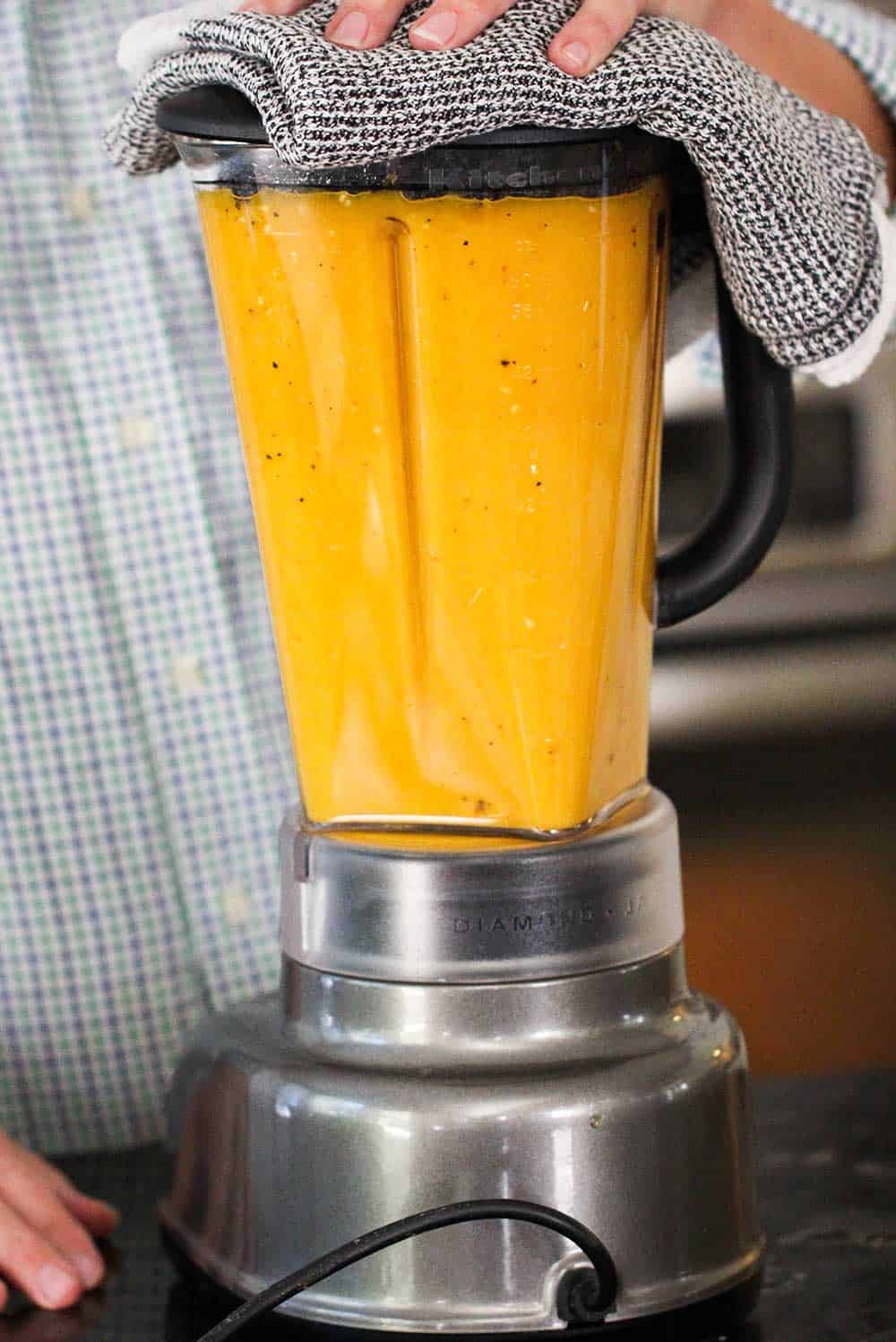 A blender full of roasted butternut squash soup that has been pureed. 