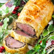 Classic Beef Wellington on a platter with Christmas holly around it