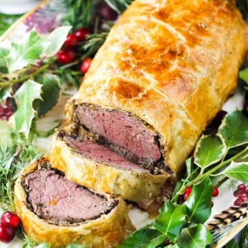 Classic Beef Wellington on a platter with Christmas holly around it
