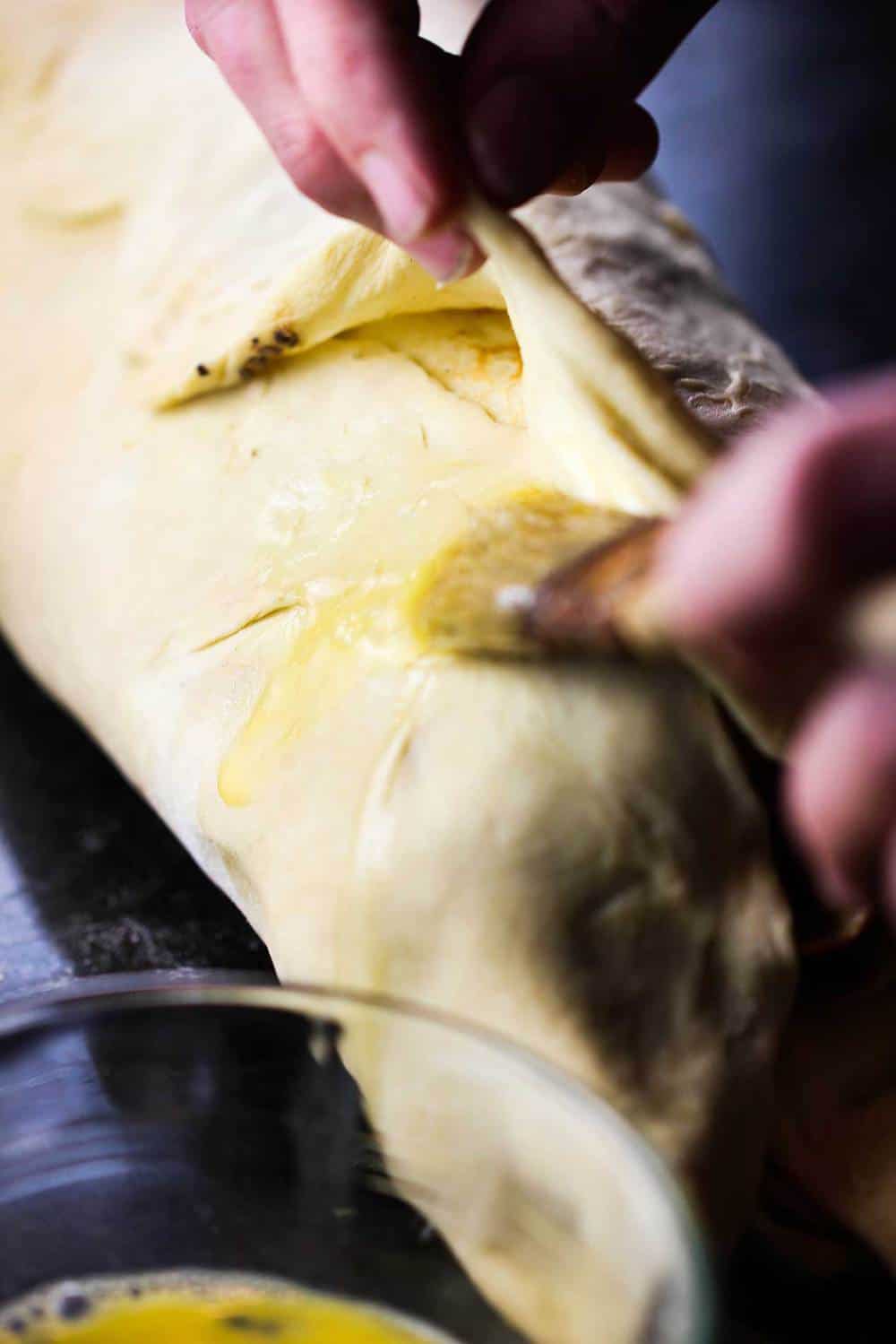 Egg wash being brushed on a classic beef Wellington