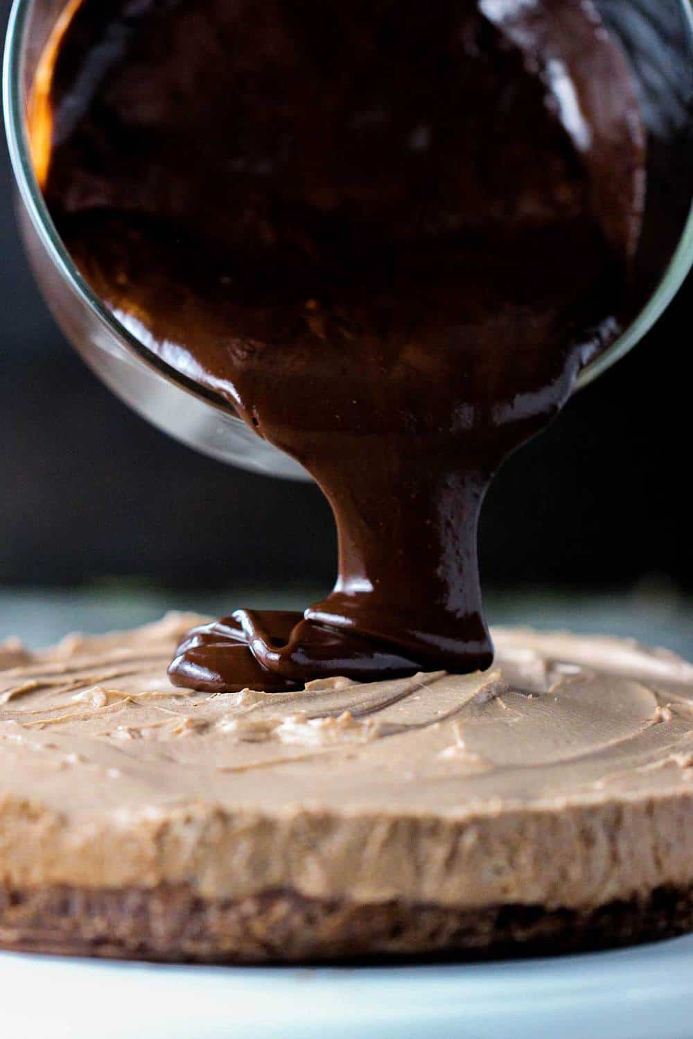 Chocolate ganache being poured on chocolate mousse cake.