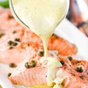 Poached salmon with hollandaise sauce being poured on top