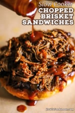 Homemade barbecue sauce being drizzled out of a glass bottle onto chopped brisket that is sitting on a toasted bun.