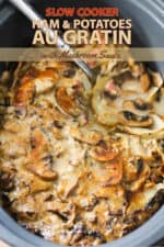 A top view of ham and potatoes au gratin in a large slow-cooker with a spoon in it.