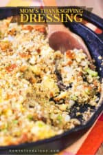 A large cast iron skillet filled with Thanksgiving dressing with a wooden spoon in it.