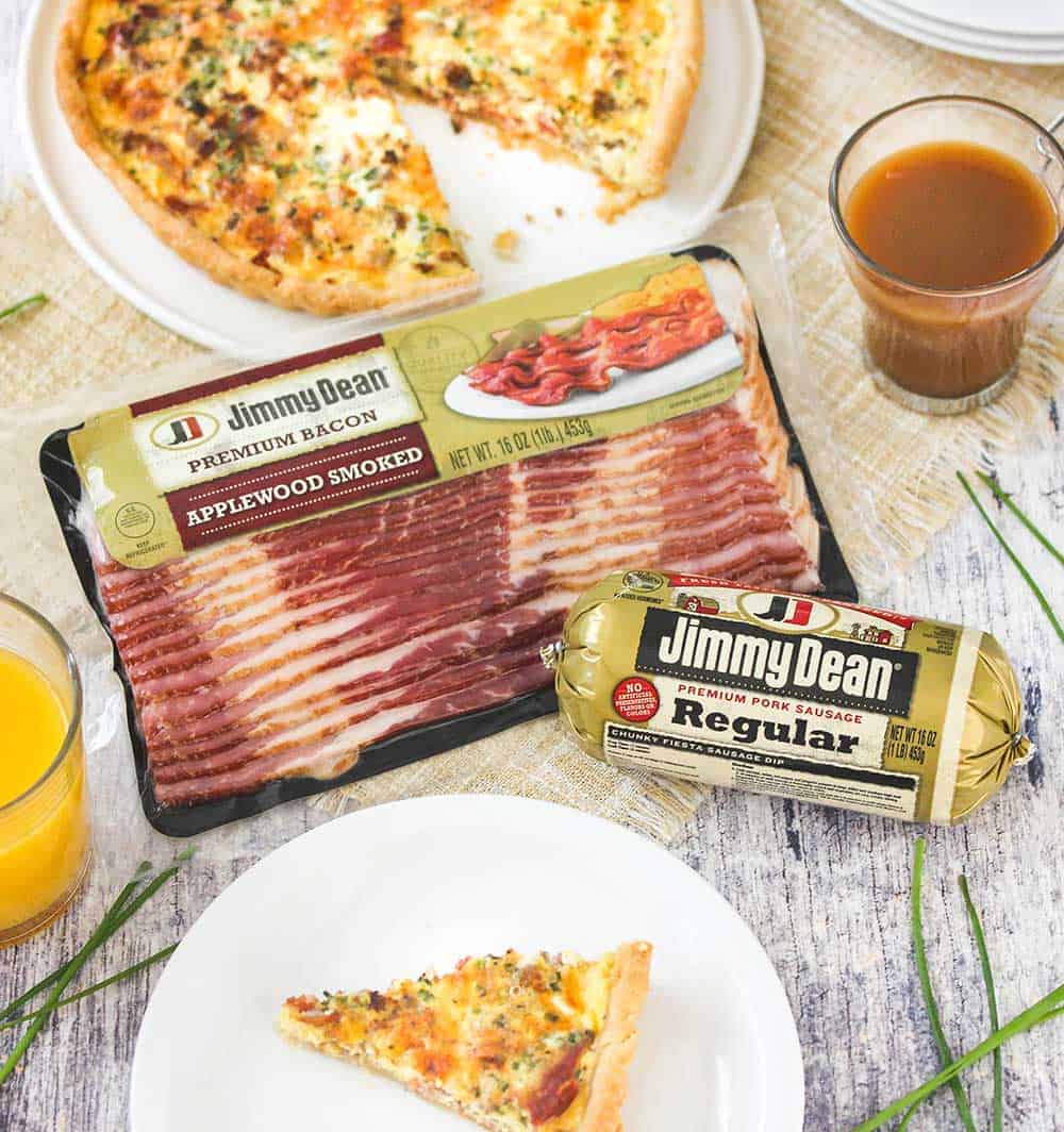 A package of smoked sausage and a package of pork sausage next to a plate of sliced breakfast quiche and a cup of coffee. 