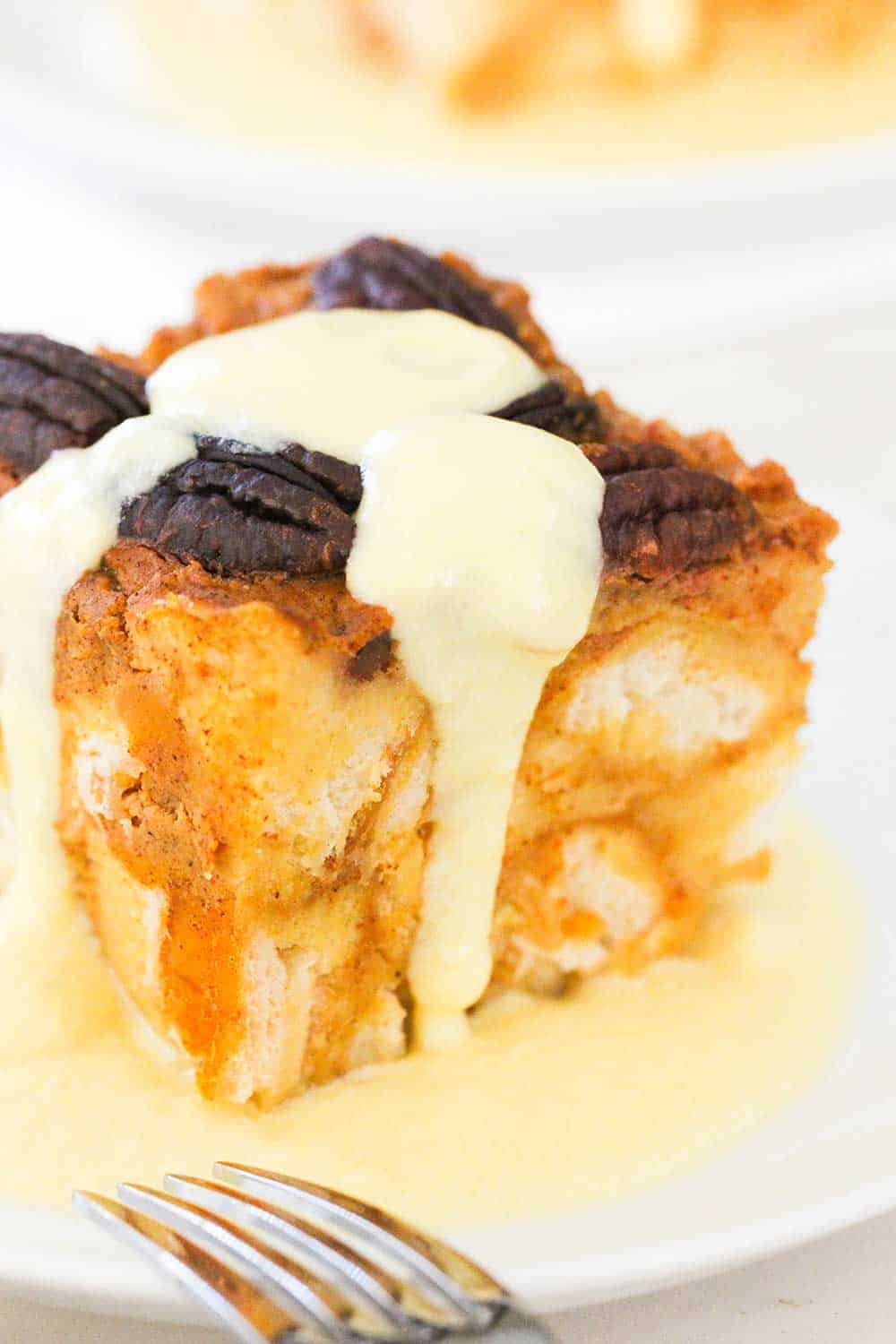A plate of pressure cooker pumpkin bread pudding with vanilla custard sauce drizzled on top. 
