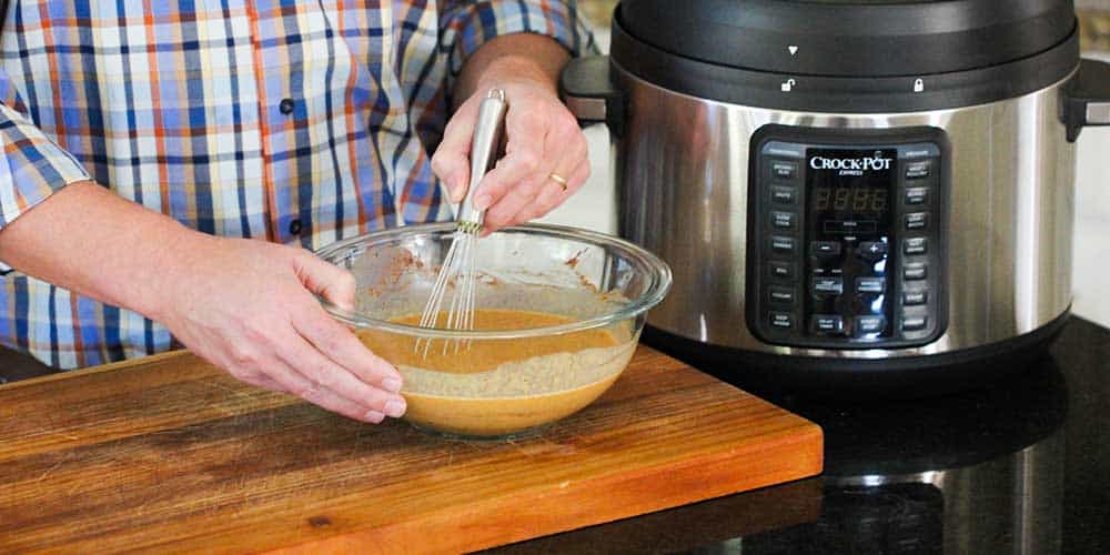 A person whisking a bowl of an egg mixture for bread pudding. 