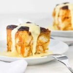 A plate of pressure cooker pumpkin bread pudding with vanilla custard sauce drizzled on top.