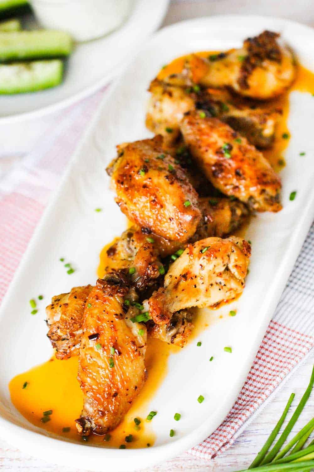 A white platter of best-ever baked hot wings sprinkled with snipped chives. 